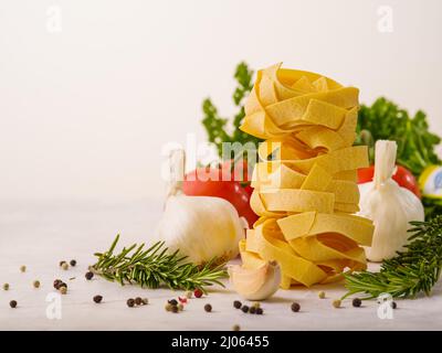 Pasta italiana, erbe aromatiche, rametti di rosmarino, pomodori, aglio su sfondo bianco. Cucina italiana, prodotti biologici sani. Ristorante, hotel, caffetteria, foo Foto Stock