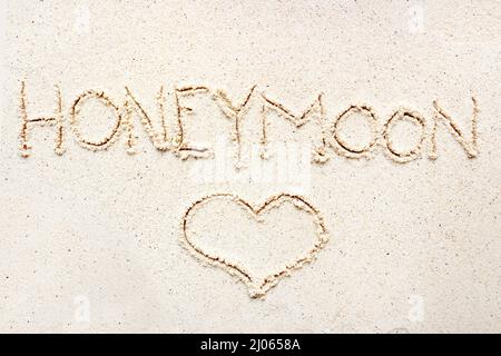 Scrivere a mano le parole 'Luna di Miele' sulla sabbia della spiaggia Foto Stock