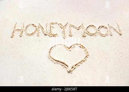 Scrivere a mano le parole 'Luna di Miele' sulla sabbia della spiaggia Foto Stock