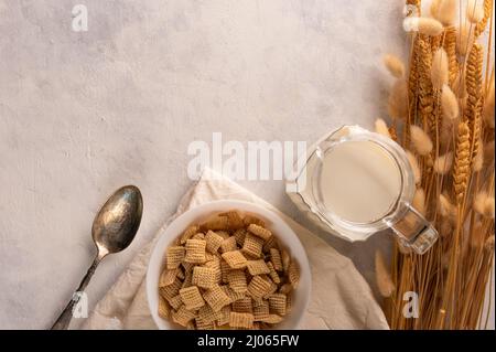 Cialde di grano intero in una ciotola, latte e un mazzo di cereali su sfondo bianco. Vista ad angolo basso. Il concetto è la prima colazione veloce cereali, sano Foto Stock