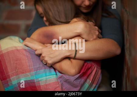 Tutto va bene Donna abusata che abbraccia la figlia spaventata. Foto Stock