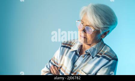 La signora pensionata europea, pensiva e a armi incrociate, si preoccupava di qualcosa. Concetto di pensionamento solitario. Foto di alta qualità Foto Stock