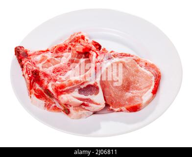 Pezzi di bistecche di lombo di maiale crudo sul piatto. Isolato su sfondo bianco Foto Stock