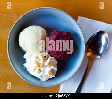 Gelato alla frutta dolce, sorbetto in palle in un piatto di ceramica su un tavolo in un ristorante Foto Stock