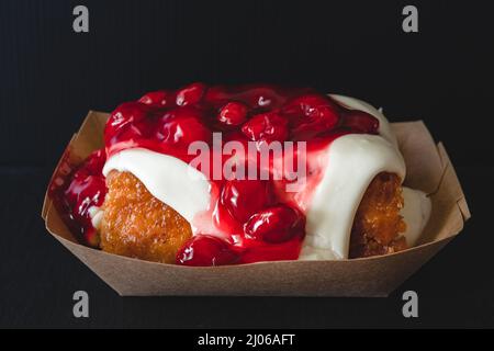 Rotolo di cannella Frosted Cherry da vicino su sfondo nero Foto Stock