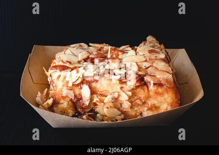 Rotolo di cannella ghiacciato di mandorla da vicino su sfondo nero Foto Stock