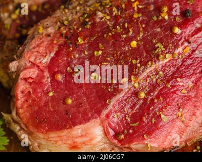 Scatto macro. Bistecca succosa cosparsa di sale e spezie. Il concetto è la cottura di bistecche di manzo, vitello, maiale. Cibo organico, proteine. Ristorante, hotel Foto Stock