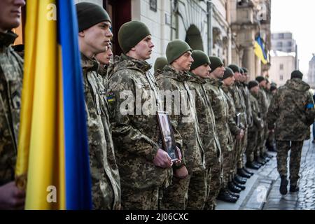 Lviv, Ucraina. 14th Mar 2022. I soldati si levano fuori da una chiesa prima del servizio commemorativo per tre soldati ucraini caduti. I lutto pagano gli ultimi rispetti a tre soldati caduti che sono stati uccisi nel 13 marzo 2022, attacco aereo russo sulla base militare di addestramento Yavoriv. Le autorità locali hanno riferito che 35 persone sono state uccise e 134 ferite alla base, che si trova vicino al confine occidentale dell'Ucraina con la Polonia. (Credit Image: © Laurel Chor/SOPA Images via ZUMA Press Wire) Foto Stock