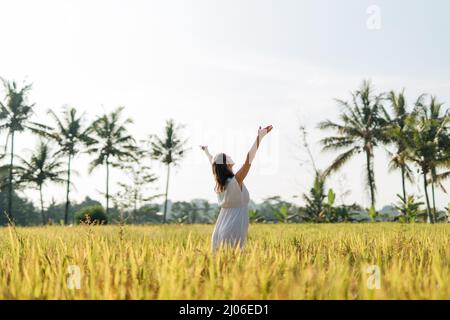 Donna incinta che va in campo con erba verde e danza con volto felice. Sole estate vibes Foto Stock