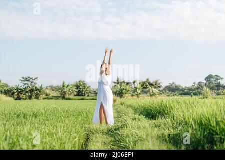 Donna incinta che va in campo con erba verde e danza con volto felice. Sole estate vibes Foto Stock