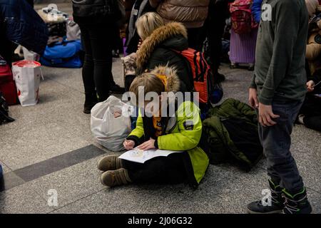 Cracovia, Polonia. 16th Mar 2022. Un bambino si siede sul pavimento mentre si attinge su un pezzo di carta alla stazione ferroviaria di Cracovia. Gli ultimi dati dell'Alto Commissariato delle Nazioni Unite per i rifugiati (UNHCR) mostrano che più di tre milioni di ucraini sono fuggiti dal loro paese in Europa a causa dell'invasione russa. Quasi 2/3 di questi rifugiati hanno deciso di risiedere in Polonia. Credit: SOPA Images Limited/Alamy Live News Foto Stock