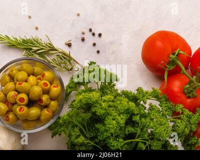 Su sfondo bianco olive verdi in una ciotola, erbe e pomodori. Vitamina fresca alimenti biologici. Cucina, ingredienti per insalata. Alimenti utili di dieta. Sano li Foto Stock