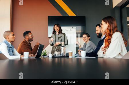 Allegra donna d'affari che fa una presentazione in una sala riunioni. donna d'affari che presenta la sua strategia aziendale ai colleghi. Gruppo di multirazziali Foto Stock