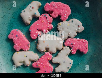 Cookie animale da circo glassato, cracker di animali rosa e bianco con spolverini sulla piastra per capezzoli Foto Stock