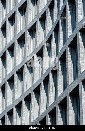Primo piano sulla facciata di un edificio con molte finestre. Moderno edificio in mattoni con interessante architettura astratta. Foto Stock