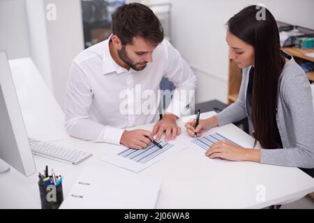 Impostazione della pianificazione mensile. Immagine di due giovani colleghi di lavoro che discutono di documenti in ufficio. Foto Stock