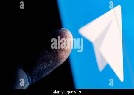 Il dito raggiunge il logo Telegram Messenger sullo schermo dello smartphone. Foto Stock