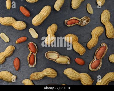 vista dall'alto delle arachidi tostate con e senza guscio su tavola in ardesia nera Foto Stock