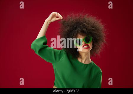 donna con acconciatura afroche indossa occhiali labbra rosse in posa Foto Stock