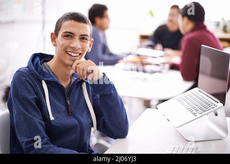 Lavorare sodo su un design nuovo di zecca. Scatto corto di un bel giovane uomo che lavora sul suo portatile in ufficio. Foto Stock