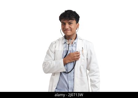 Ritratto di un giovane medico peruviano maschio utilizzando lo stetoscopio su di lui, isolato. Foto Stock