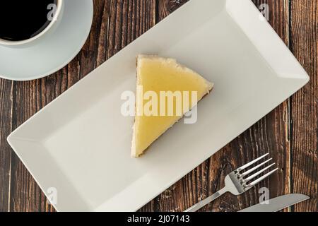 Deliziosa cheesecake al limone servita con caffè su tavola di legno Foto Stock