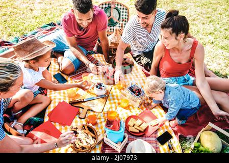 Famiglie multirazziali divertirsi insieme ai bambini al parco su pic nic party - gioia genuina e amore stile di vita concetto con età mista persone tostando j Foto Stock