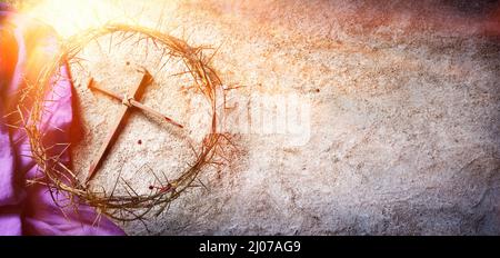 Passione e Crocifissione di Gesù - Corona di spine e chiodi sanguinosi e Robe viola a terra con luce solare e fuoco selettivo Foto Stock