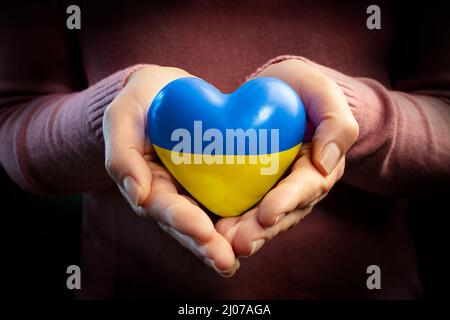 Pregate per l'Ucraina - mani con cuore e bandiera Ucraina - Pace e No War Concept Foto Stock