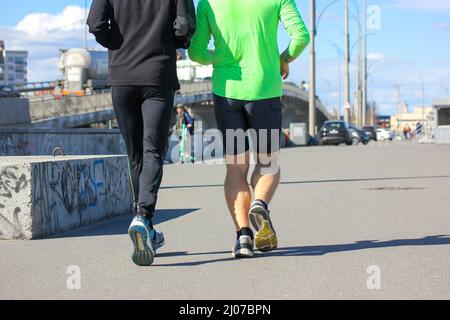 Due uomini atletici al mattino scherzano al sole del mattino. Ragazzi atletici che fanno jogging insieme Foto Stock