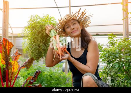 Donna felice con mazzo di carote appena raccolte nel giardino sul cortile. Agricoltura biologica, cibo sano stile di vita da fattoria a tavola. Foto Stock