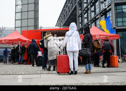 Berlino, Germania. 17th Mar 2022. I rifugiati ucraini si accodano fuori dalla stazione ferroviaria principale di Berlino per ottenere le carte SIM da un'auto appartenente alla società di telecomunicazioni Vodafone. I rifugiati ucraini ricevono una carta SIM per il loro smartphone gratuitamente per tre mesi e possono così tenersi in contatto con la loro patria gratuitamente. Alla stazione ferroviaria della capitale tedesca giungono ogni giorno diverse migliaia di persone, e si prevede che il numero dei rifugiati ucraini continui ad aumentare. Credit: Bernd von Jutrczenka/dpa/Alamy Live News Foto Stock