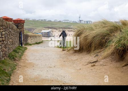 Un uomo Cycles lungo la cima della scogliera a Newquay, Cornovaglia, regno unito Foto Stock