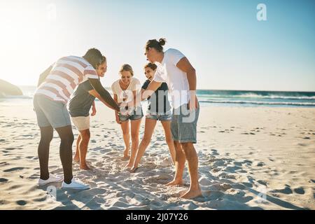 Promette di rendere quest'estate la migliore di sempre. Colpo di un gruppo di giovani che si uniscono in solidarietà alla spiaggia. Foto Stock