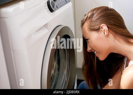 Il suo giorno di lavanderia. Scatto corto della giovane donna che fa il bucato a casa. Foto Stock