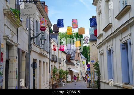 AZAY-LE-RIDEAU, FRANCIA -24 GIU 2021- Vista sulla strada del villaggio di Azay-le-Rideau, casa di un castello rinascimentale di riferimento, con lantere in tessuto sospeso Foto Stock