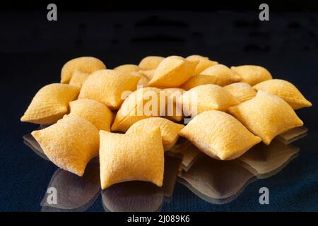 Patatine su un tavolo di vetro con un riflesso. Cibo su sfondo nero Foto Stock