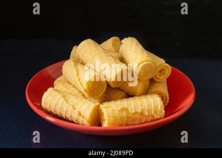 Preparare i tubi in un piatto rosso sul tavolo. Cibo su sfondo nero Foto Stock