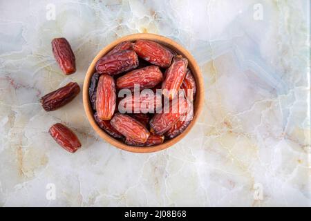 Ciotola di frutta datteri su sfondo di marmo colorato, vista dall'alto Foto Stock