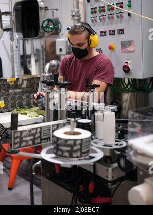 Uomo che lavora imballaggio lattine di birra in una fabbrica Foto Stock