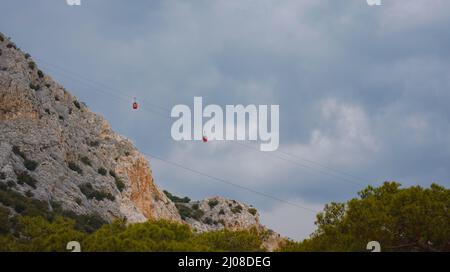 Cabine rosse di funicolare ad Antalya, Turchia sullo sfondo di nuvole di pioggia. Gita in funivia ai punti panoramici delle montagne. Durante il viaggio in funivia Touris Foto Stock