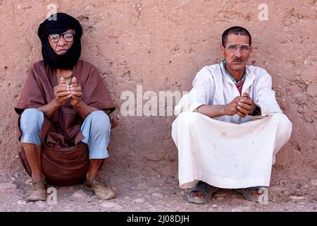 Due uomini locali seduti all'ombra in una città desertica di M'Hamid, nel sud del Marocco, in Africa Foto Stock
