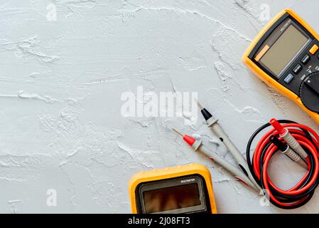 Multimetro digitale giallo con sonde su sfondo bianco con spazio di copia libero. Foto Stock