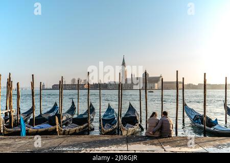 Coppia in amore avendo data a Venezia, Italy.Famous canale e gondole tradizionali, chiesa di San Giorgio maggiore in background.stile di vita città veneziana, tra Foto Stock