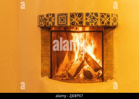 kiva stile camino bruciando tronchi comuni nelle case nel sud-ovest degli Stati Uniti con le pareti adobe irradiando calore e fornire calore accogliente Foto Stock