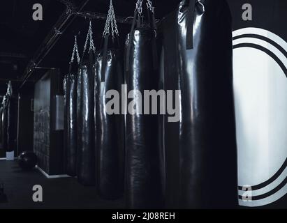 Mantenere la calma e il box on. Ancora vita sparato di una fila di sacchetti di punzonatura in una palestra. Foto Stock
