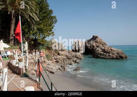 Piccola Cove nel Mediterraneo, Nerja, Costa del Sol, Provincia di Malaga, Andalusia, Spagna. Bagnanti, ombrelloni, lettini Foto Stock