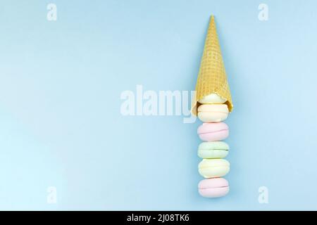 Delizioso sotto forma di un cono di waffle girano in su e marshmallows ripieni assomiglia ai macaroon su uno sfondo blu Foto Stock