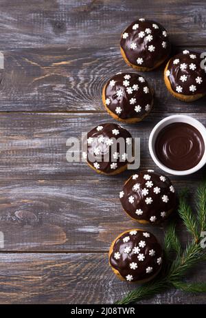 Muffin piccanti di zucca con noci, decorati con glassa al cioccolato e fiocchi di neve sotto l'albero di Natale su un tavolo di legno, spazio libero, selettivo Foto Stock