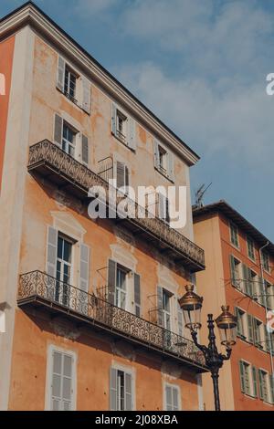 Facciata di un tradizionale edificio antico nella città vecchia di Nizza, Francia, in una giornata di sole, vista ad angolo basso contro il cielo blu. Foto Stock